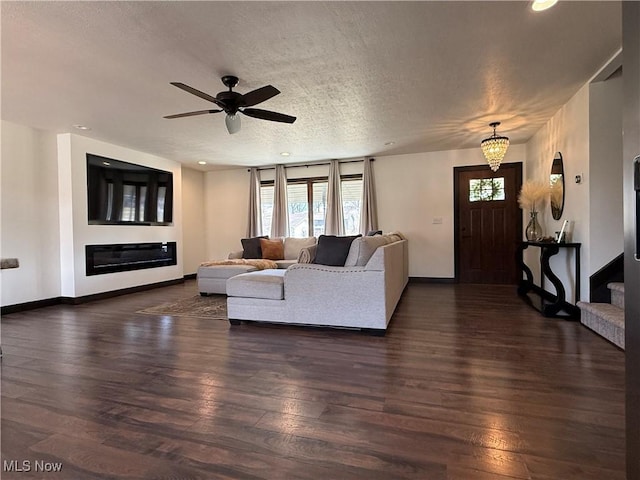 living area with stairway, a textured ceiling, baseboards, and wood finished floors