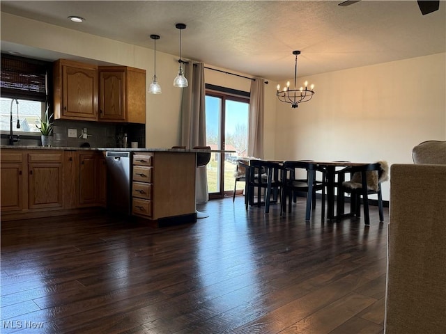 kitchen with a healthy amount of sunlight, a notable chandelier, dark wood-type flooring, and stainless steel dishwasher