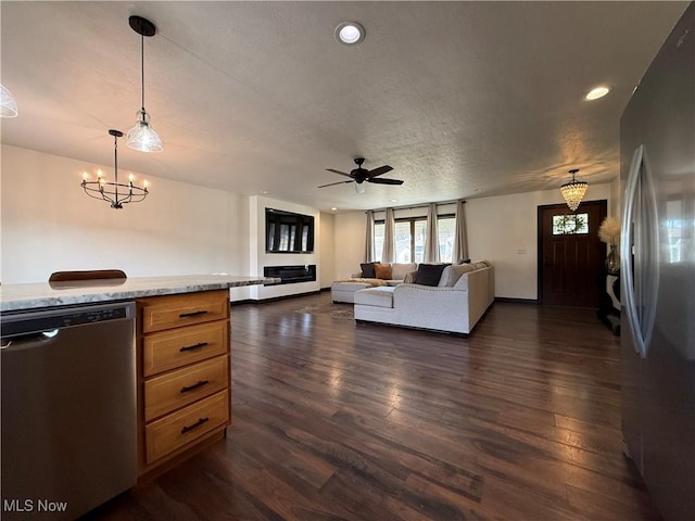 living area with a textured ceiling, ceiling fan with notable chandelier, dark wood-type flooring, and recessed lighting