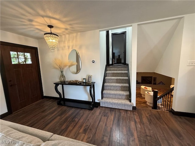 foyer entrance with baseboards, stairway, wood finished floors, and an inviting chandelier