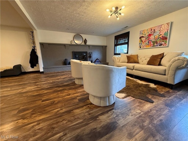 living room featuring a chandelier, visible vents, a textured ceiling, and wood finished floors