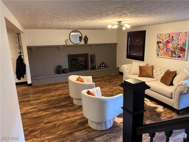 living room with a notable chandelier, a textured ceiling, a fireplace, and wood finished floors