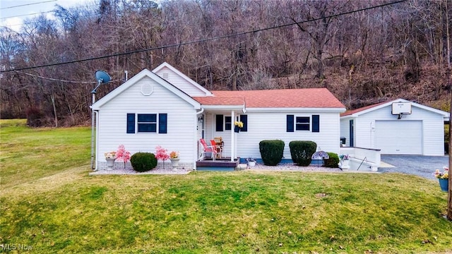 ranch-style house with an outbuilding, a detached garage, driveway, a forest view, and a front lawn