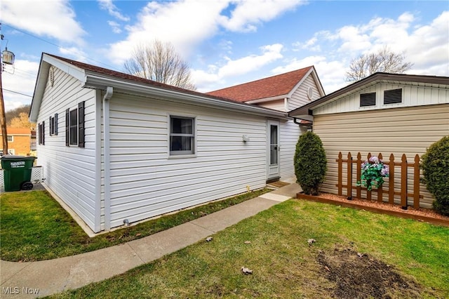 view of side of home featuring a lawn and fence