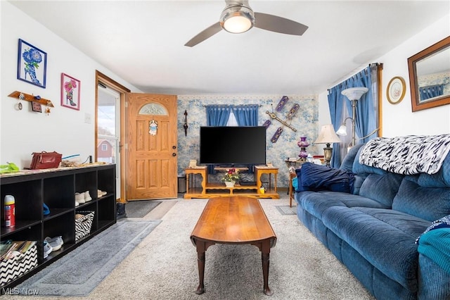 living room featuring an accent wall, a ceiling fan, carpet flooring, and wallpapered walls