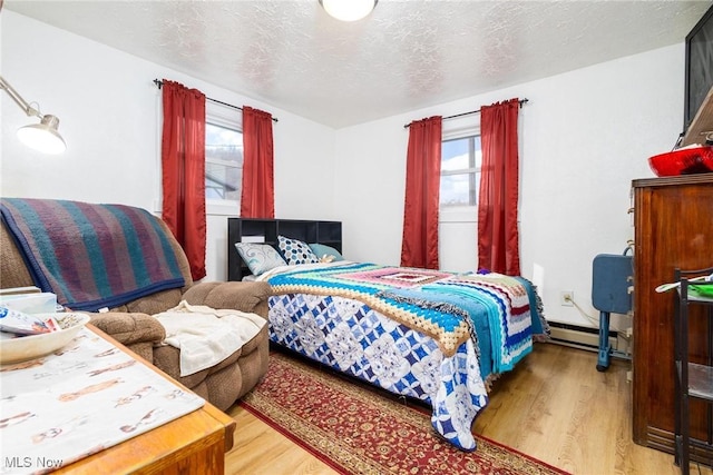 bedroom with a textured ceiling, baseboard heating, and wood finished floors