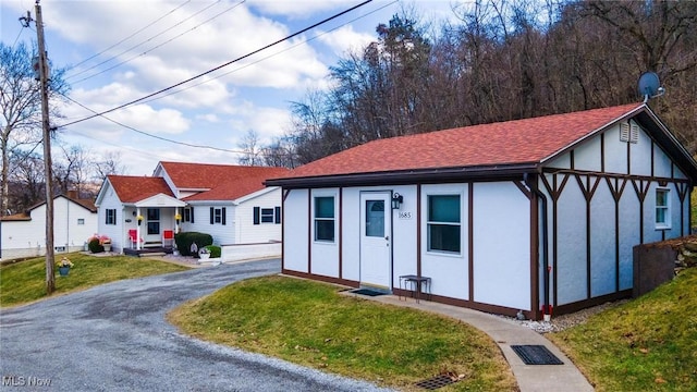 view of front of home with stucco siding, a shingled roof, aphalt driveway, and a front yard