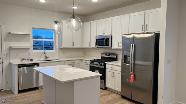 kitchen featuring light wood-style flooring, a sink, tasteful backsplash, a center island, and appliances with stainless steel finishes