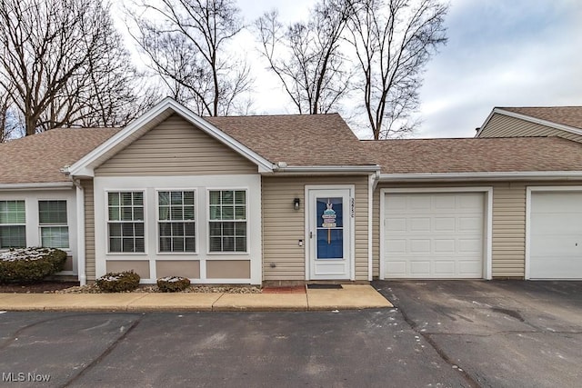 ranch-style house featuring roof with shingles, driveway, and an attached garage