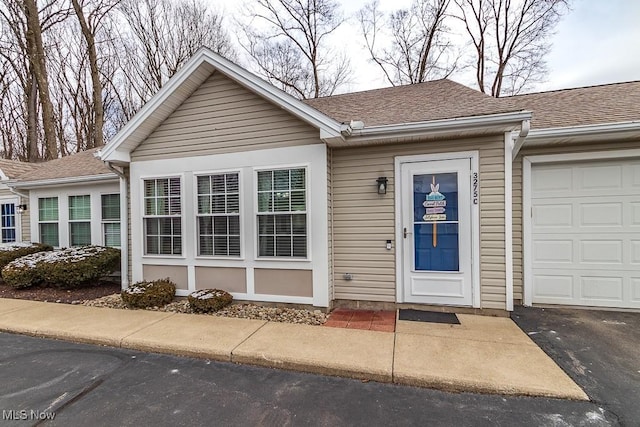 single story home featuring a garage and roof with shingles