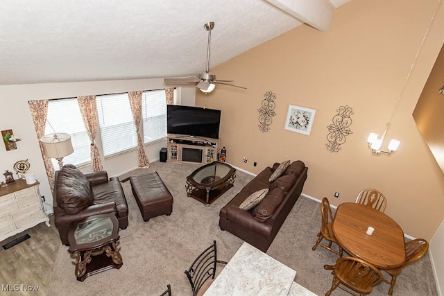 living area with baseboards, ceiling fan, vaulted ceiling with beams, carpet, and a textured ceiling