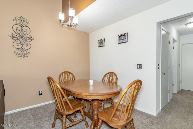 carpeted dining area with baseboards and a notable chandelier