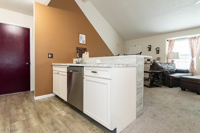 kitchen featuring lofted ceiling, light countertops, open floor plan, white cabinets, and dishwasher