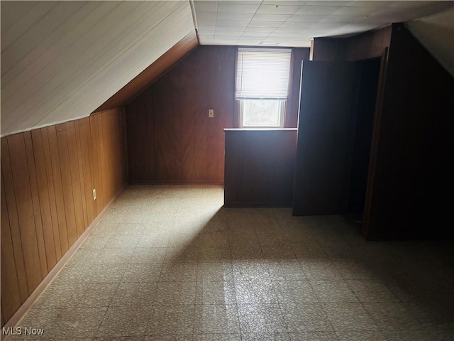 bonus room featuring lofted ceiling, wooden walls, and tile patterned floors