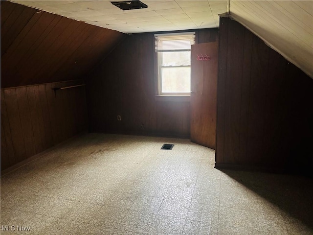 bonus room with vaulted ceiling, visible vents, wood walls, and light floors