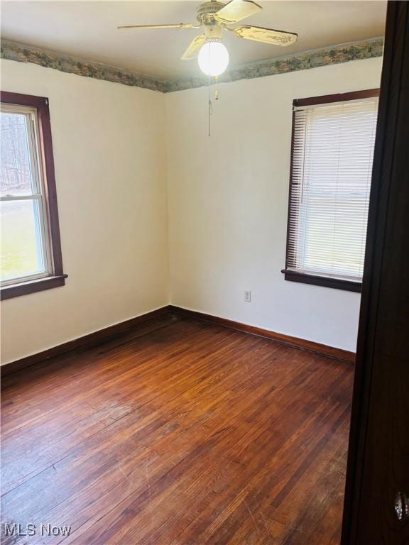 spare room with ceiling fan, dark wood-style flooring, and baseboards