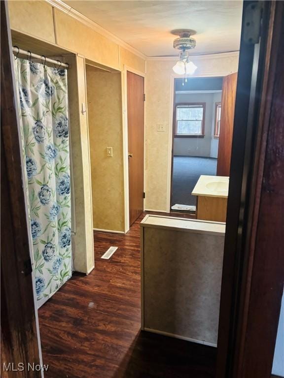 hall featuring dark wood-type flooring, visible vents, and crown molding