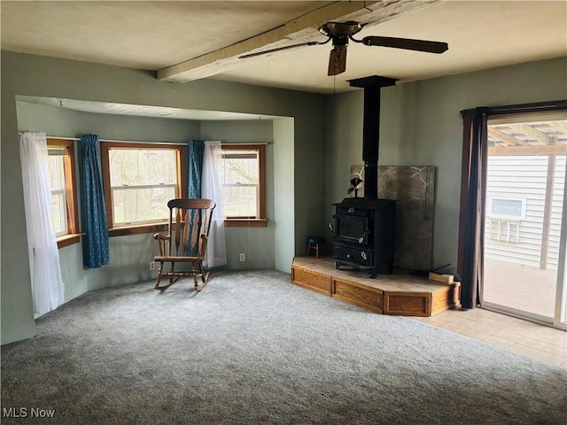 living area with ceiling fan, carpet floors, and a wood stove