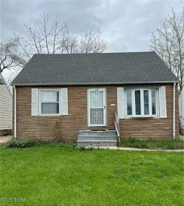 view of front of home featuring entry steps, stone siding, a shingled roof, and a front lawn