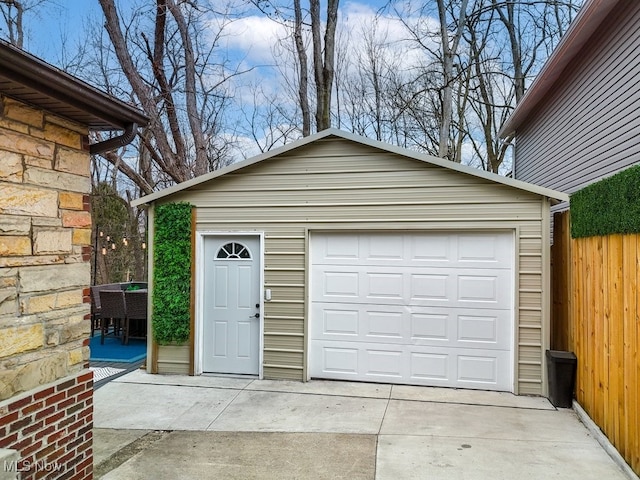 detached garage featuring driveway and fence