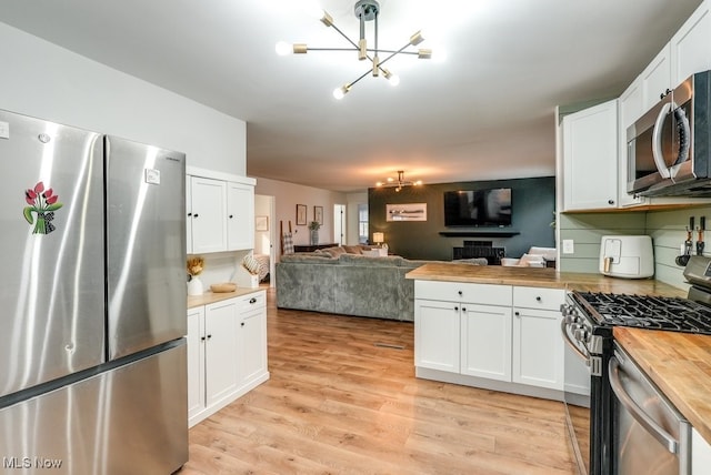 kitchen with stainless steel appliances, light wood-type flooring, a chandelier, and butcher block countertops