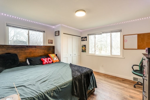 bedroom featuring a closet, visible vents, light wood-style flooring, and baseboards