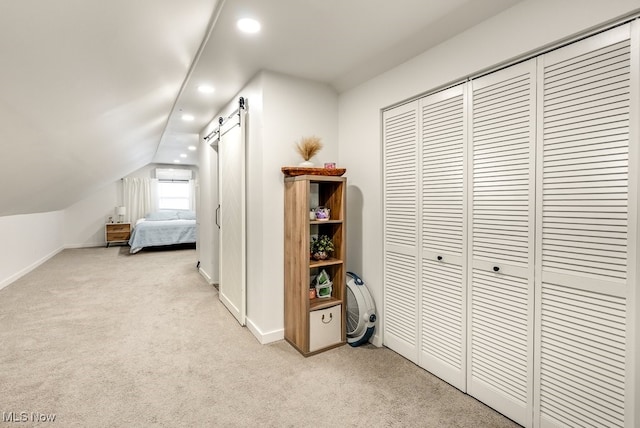 bedroom featuring a wall mounted air conditioner, carpet flooring, vaulted ceiling, and a barn door