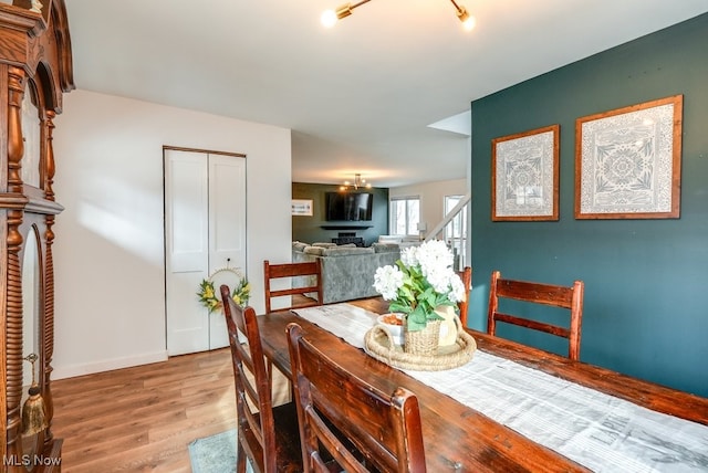 dining area featuring stairway, a notable chandelier, light wood-style flooring, and baseboards