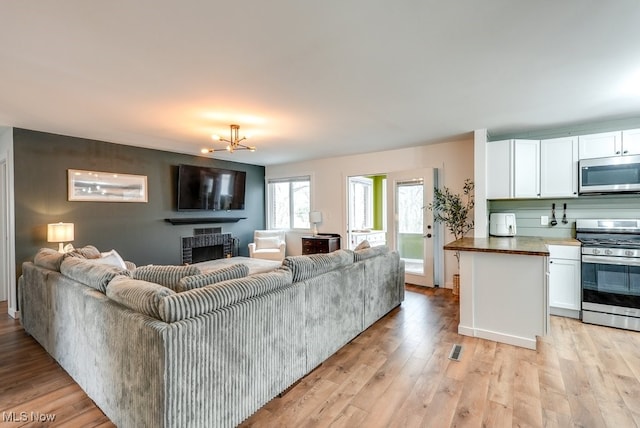 living area featuring light wood finished floors, a fireplace, and a notable chandelier