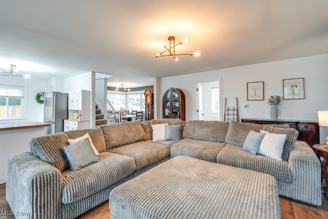 living area with stairway, wood finished floors, and a notable chandelier