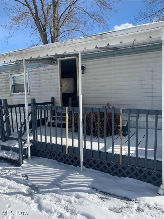 snow covered property entrance with fence