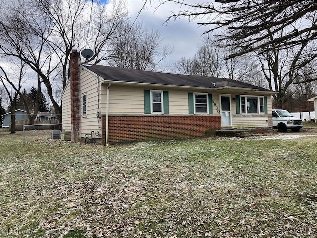 view of front of home featuring a chimney, fence, central air condition unit, a front lawn, and brick siding