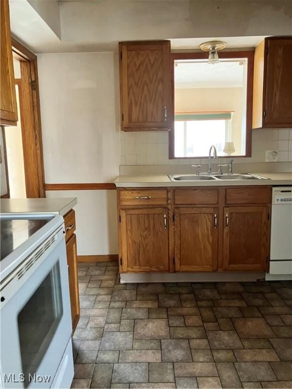 kitchen with tasteful backsplash, white appliances, light countertops, and a sink