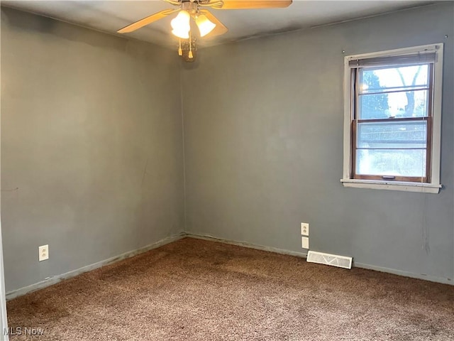 empty room featuring carpet floors, visible vents, baseboards, and a ceiling fan