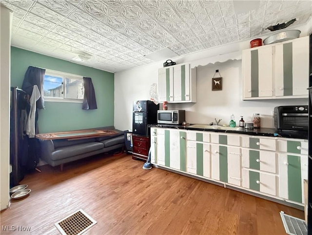 328 Scott Ave, Niles, OH 44446 - kitchen featuring stainless steel microwave, an ornate ceiling, light wood-style flooring, white cabinets, and dark countertops