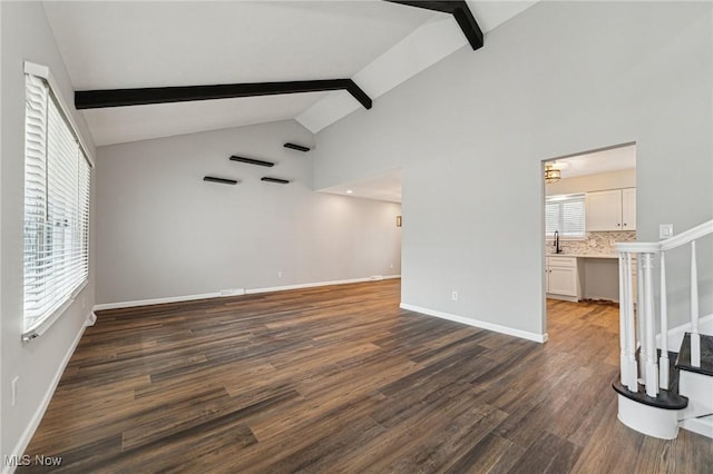 unfurnished living room featuring a sink, baseboards, stairway, beamed ceiling, and dark wood finished floors