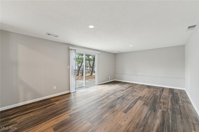 unfurnished room with baseboards, visible vents, and dark wood-type flooring