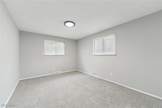 carpeted spare room featuring visible vents and baseboards