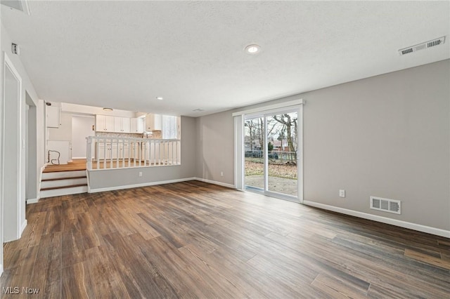 unfurnished living room featuring dark wood-style floors, visible vents, and baseboards