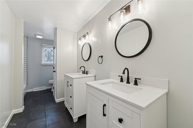 bathroom featuring toilet, visible vents, two vanities, and a sink