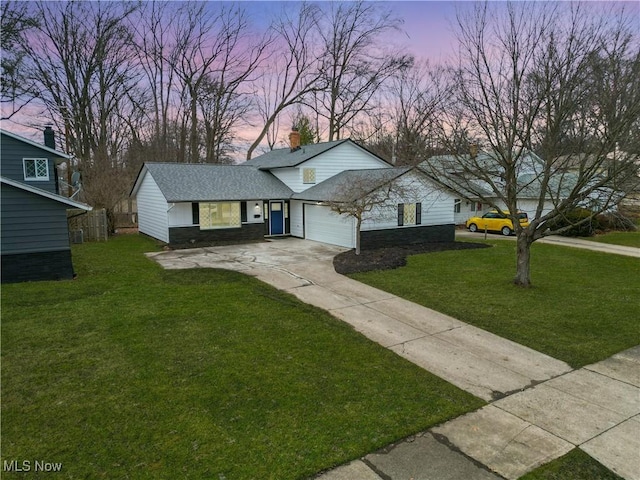 view of front of property featuring roof with shingles, a yard, concrete driveway, a garage, and stone siding