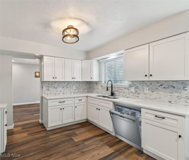 kitchen with dark wood-style flooring, a sink, white cabinets, stainless steel dishwasher, and backsplash