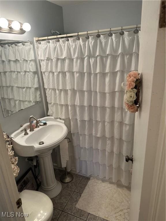 full bath featuring a shower with curtain, a sink, and tile patterned floors