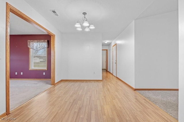 unfurnished room featuring a chandelier, light wood-style flooring, light carpet, visible vents, and baseboards