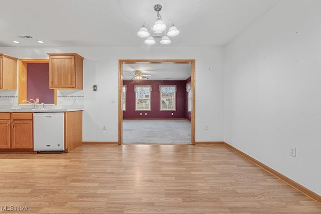 kitchen featuring light wood finished floors, baseboards, white dishwasher, light countertops, and backsplash