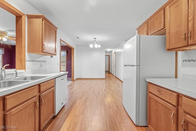 kitchen with white appliances, light countertops, a sink, and light wood finished floors