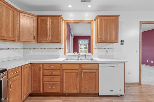 kitchen featuring tasteful backsplash, light countertops, white dishwasher, and a sink