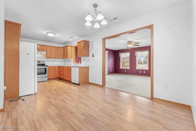 kitchen with white appliances, visible vents, light wood-style floors, light countertops, and under cabinet range hood