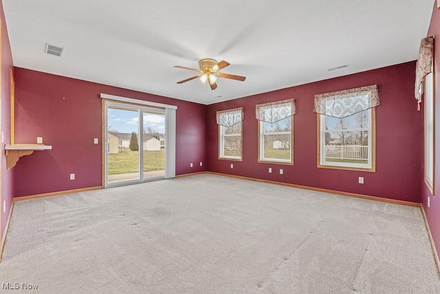 carpeted spare room featuring ceiling fan, visible vents, and baseboards