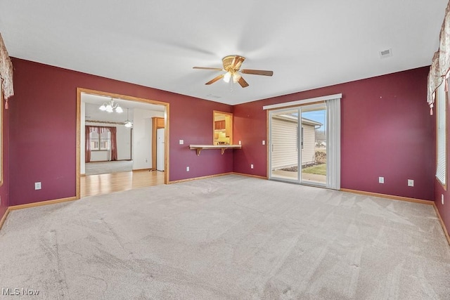 carpeted spare room featuring baseboards, visible vents, and ceiling fan with notable chandelier